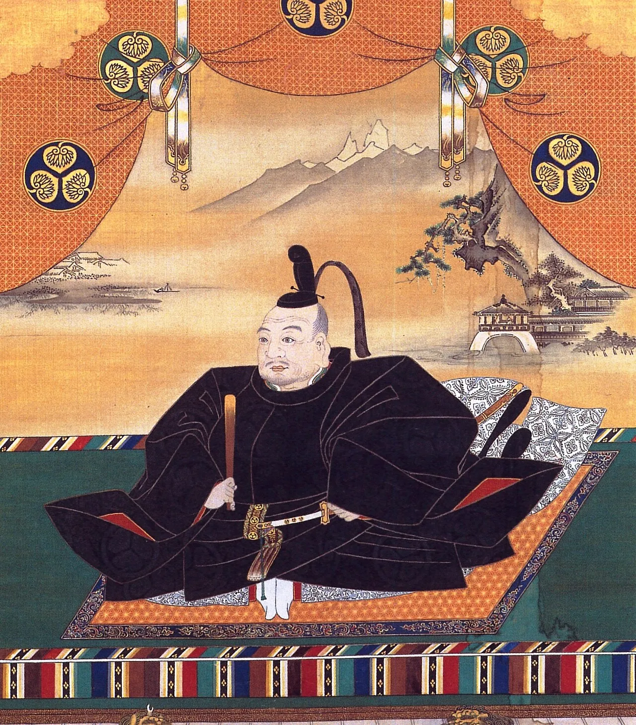 Hanging-scroll portrait of Tokugawa Ieyasu seated in black robes on a patterned mat, a landscape and triple-hollyhock crests behind him.